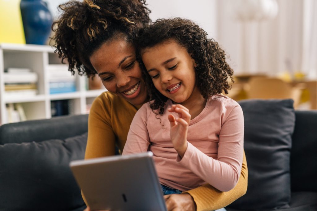 Maman tenant sa petite fille dans les bras pour lui montrer quelque chose à l'écran de sa tablette