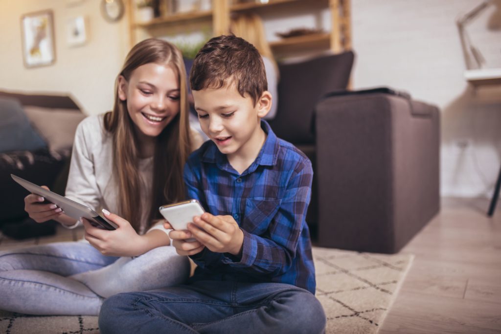 Jeunes enfants en train de jouer avec leur tablette et téléphone portable