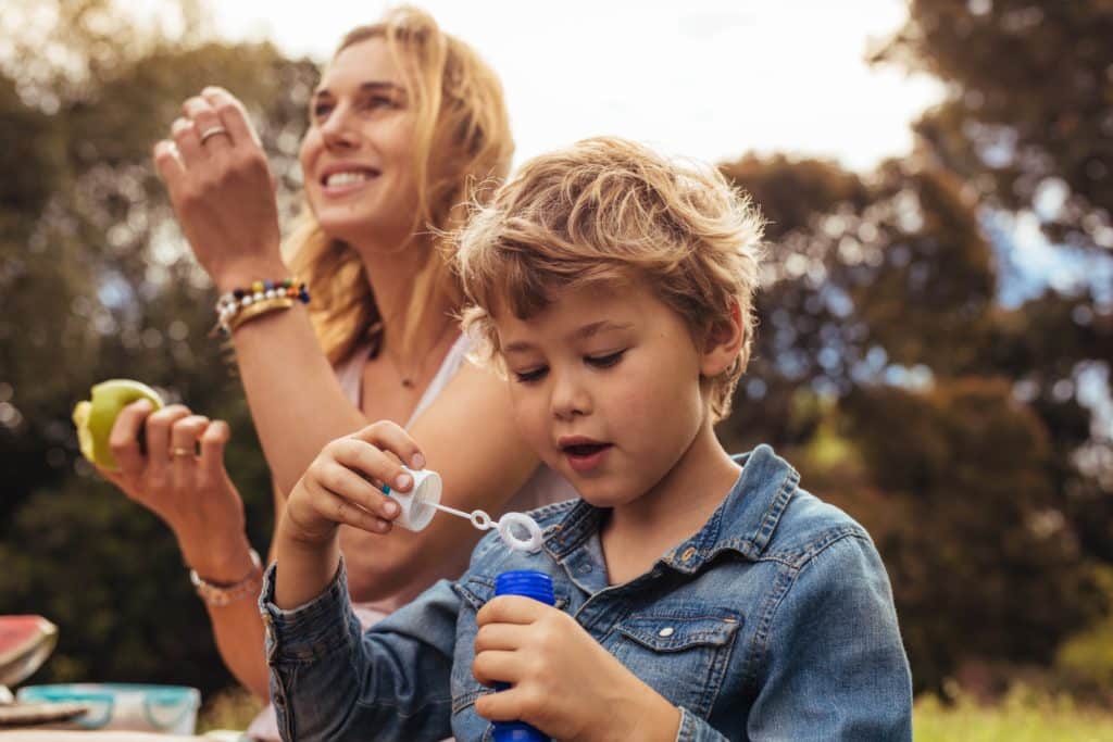 Maman et son jeune fils dans un parc en train de faire des bulles de savon