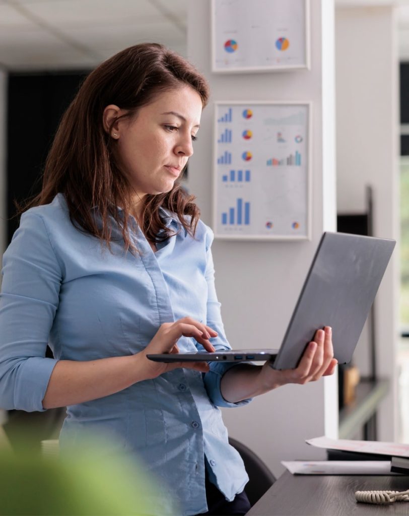 Femme au travail portant un ordinateur portable dans ses mains