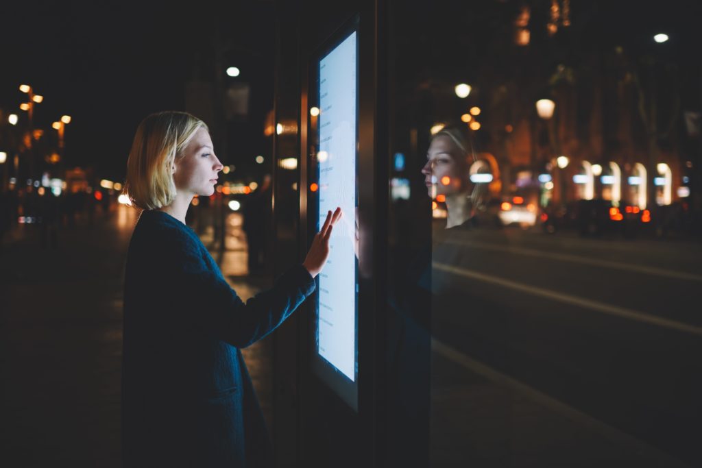 Femme en train de naviguer sur un écran digital dans la rue
