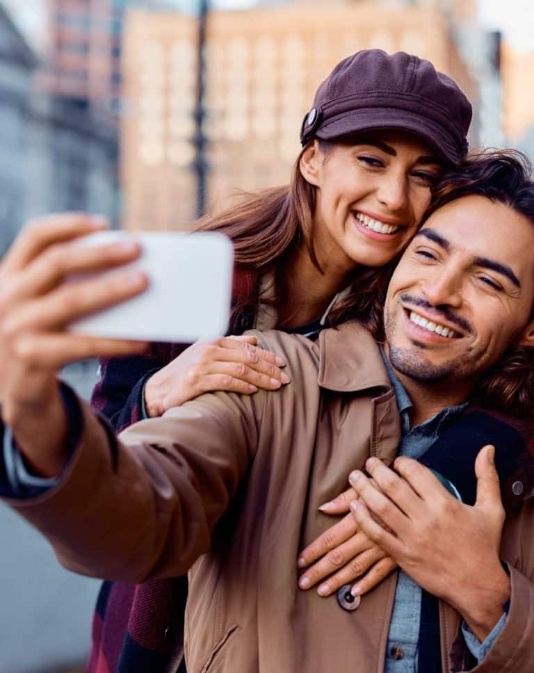 Couple dans la rue en train de prendre un selfie avec un téléphone portable