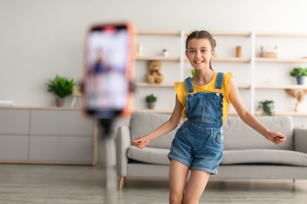 Petite fille en train de se filmer à l'aide de son téléphone portable pendant qu'elle danse