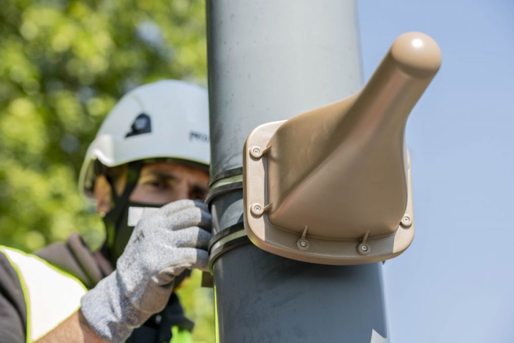 Vue d'un technicien en train d'accrocher un capteur de mesure d'ondes électromagnétiques à un candélabre